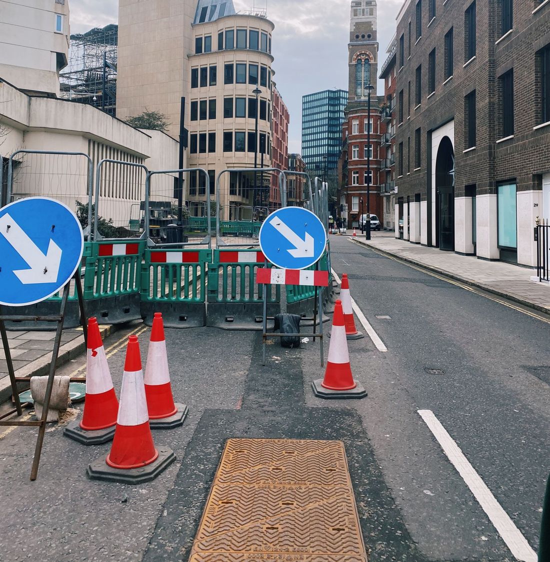 Road opening with barriers, cones and a manhole cover on a London street