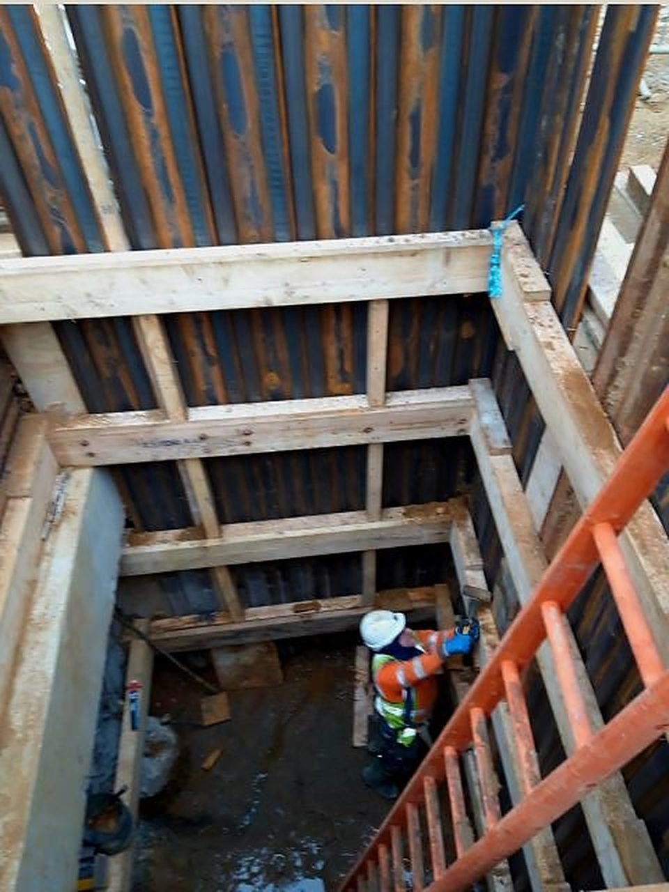 Sheet piled shaft with timber walings and an operative working at the base, London
