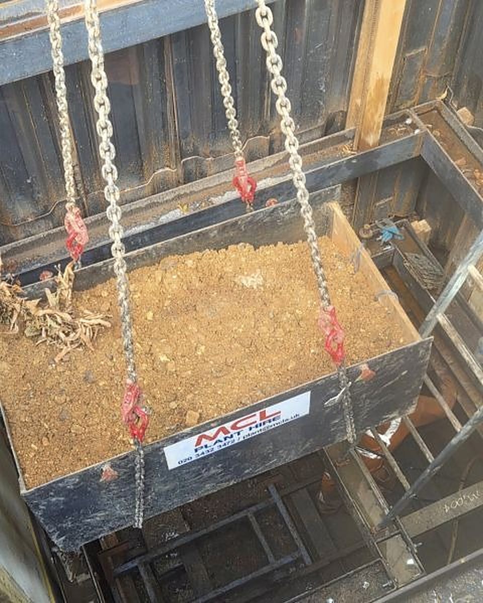 Skip of spoil labelled MCL Plant Hire lifted out of a shaft on chains